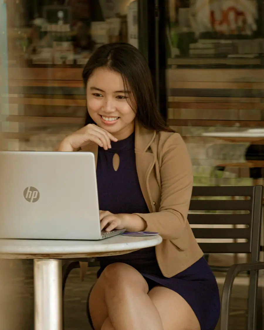 Smiling Filipina business owner working on her laptop at a café